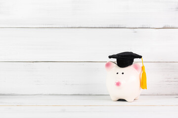 Education Hat with piggy bank on white wood background. Saving Concept.