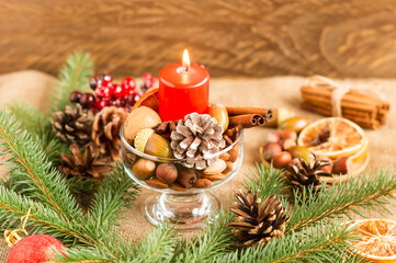 New Year's rustic decor. red candle surrounded by cones, spruce branches, nuts, zholudei. wooden background.