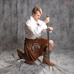 The Scottish knight knelt, took an oath, concept. A young man in a kilt