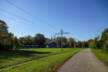 Autumnal landscape background with clear blue sky. City buses in the parking. Electric poles for...