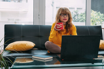middle-aged adult woman at home with computer and cup of coffee