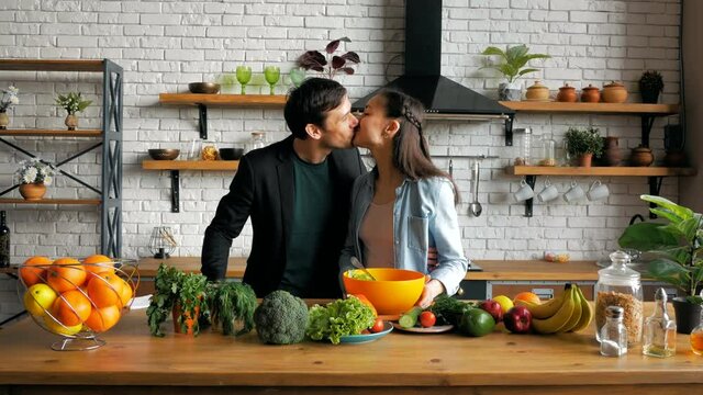 Young beautiful woman together with her beloved husband prepare a vegetable salad in the kitchen of their apartment.A happy young housewife treats her husband to dinner in her kitchen.