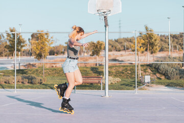 a very pretty girl riding on in-line skates on a basketball court.