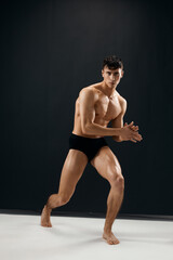 Fototapeta premium athletic men with a pumped-up muscular body black panties posing dark background