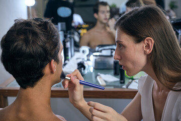Professional male model at make up before studio photo shooting