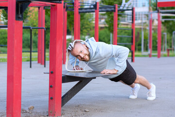 Fototapeta premium A man with an interesting mohawk hairstyle doing push-ups on the street