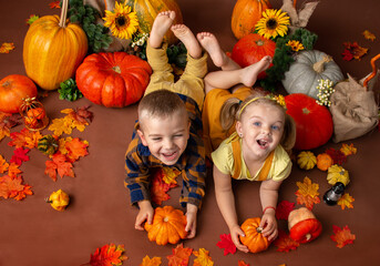 Boy with girl having fun playing with pumpkins. Studio shooting. Halloween and Thanksgiving time fun for family.