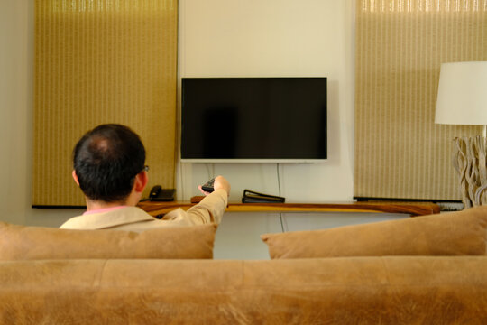 Man Watching Television On Sofa At Home, Sitting On A Sofa Watching Tv, Home Quarantine, New Normal, Relaxing At Home Concept