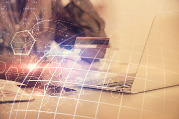 Double exposure of woman on-line shopping holding a credit card and world map hologram drawing. International E-commerce concept.