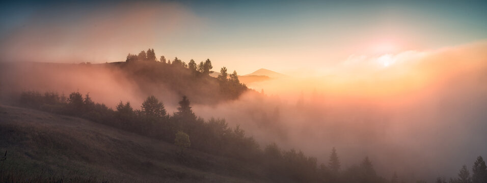 Panorama of valley covered with fog in a light
