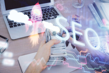Multi exposure of seo drawing hologram and us dollars bills and man hands.