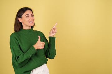 Young woman in green warm sweater happy excited cheerful point fingers to right