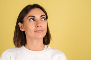 Fototapeta premium Young woman in white warm sweater happy thoughtful look right with smile
