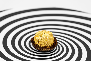 a candy wrapped in gold foil on Hypnosis visualisation conept endless spiral background