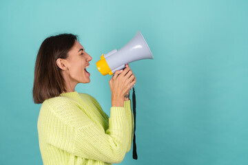 Young woman in light green sweater with megaphone happy screaming to right