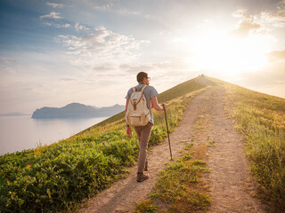 Young man travels alone walking on trail and enjoying on view of mountains and sea landscape at...