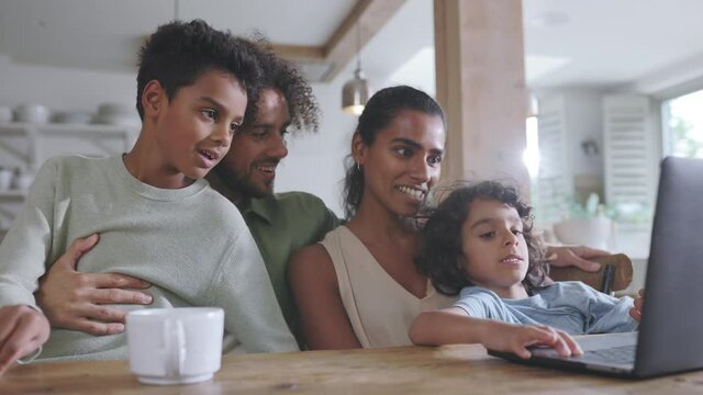 Slow motion of boys in kitchen with parents and laptop