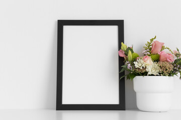 Black frame mockup with a bouquet of roses on the white table.