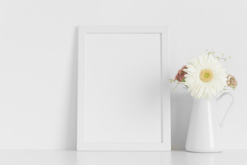 White frame mockup with a bouquet of flowers on the white table.