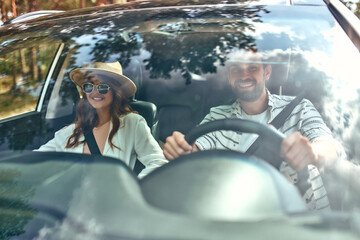 Young couple in a new car. A man driving a car with his girlfriend and having fun. Buying and...