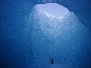 A view from within the ice cave in Iceland. The sky can be seen from the melted hole at the top of...