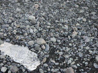 Ice berg washed on shore on pebble beach.