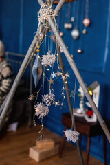 Bright shiny stars, Christmas tinsel on blue background hang on bamboo sticks of the wigwam.