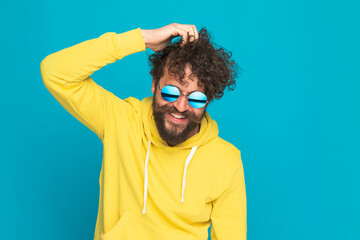 bearded man with long hair and retro glasses scratching head and smiling
