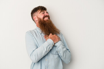 Young caucasian ginger man with long beard isolated on white background laughing keeping hands on heart, concept of happiness.