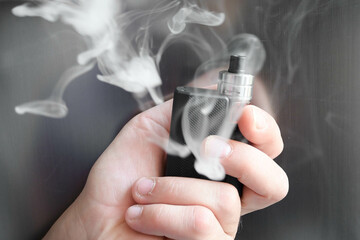 main tenant une cigarette électronique avec de la fumée