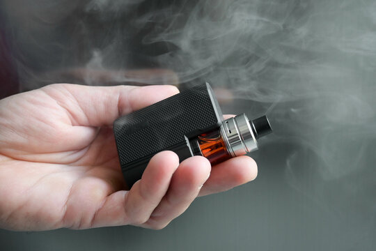 main tenant une cigarette &eacute;lectronique avec de la fum&eacute;e