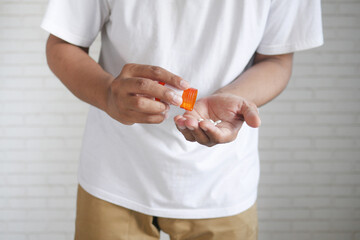 man's hand with medicine spilled out of the pill container 