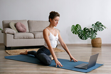 Sporty young woman teaching yoga online in the comfort of her own home. Yogini broadcasting live...