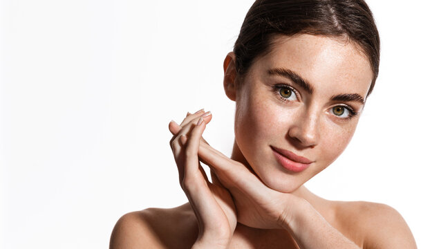 Beauty face and spa. Woman with freckles, clean nourished skin, biting lip and look aside. Girl model using antiaging cosmetics and vitamin c serum for bettet smoother skin tone, white background