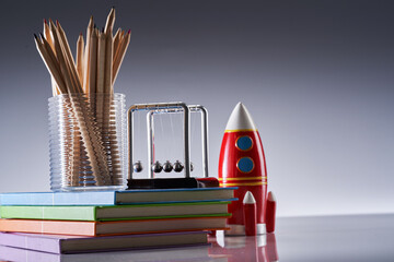 Bright toy rocket, cradle and school supplies on gray background