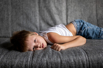 funny boy in white t-shirt posing in front of camera on couch