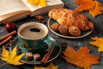 Autumn background with cup of black coffee, croissant and fall decoration