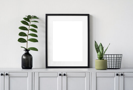 Blank picture frame mockup on gray wall. White living room design. View of modern scandinavian style interior with artwork mock up on wall. Home staging and minimalism concept