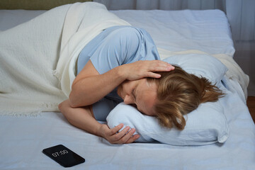 Mature woman feeling headache after sudden awakening by phone call, or alarm in early morning,...