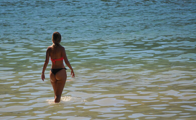 Rapariga bonita em biquíni de costas dentro de água num dia quente de verão, numa praia fluvial