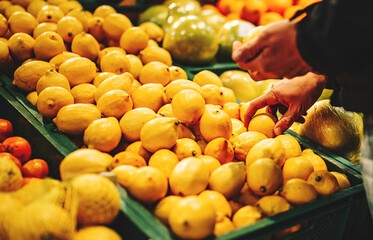 man hand holding lemon in grocery store in supermarket