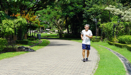 an old man is jogging among the nature atmosphere (selective focus), concept heath care, lifestyle, activity in elderly people