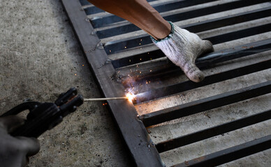 Iron gate repair, Worker hand welding steel