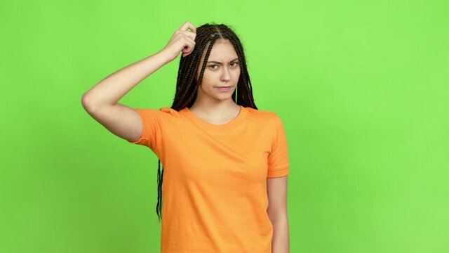 Teenager girl with braids having doubts while scratching head over isolated background. Green screen chroma key