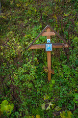 A wooden cross in the grass on a hillock with faded icons