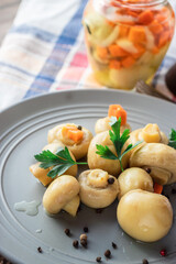 Pickled mushrooms in a gray plate in a close-up on a kitchen napkin
