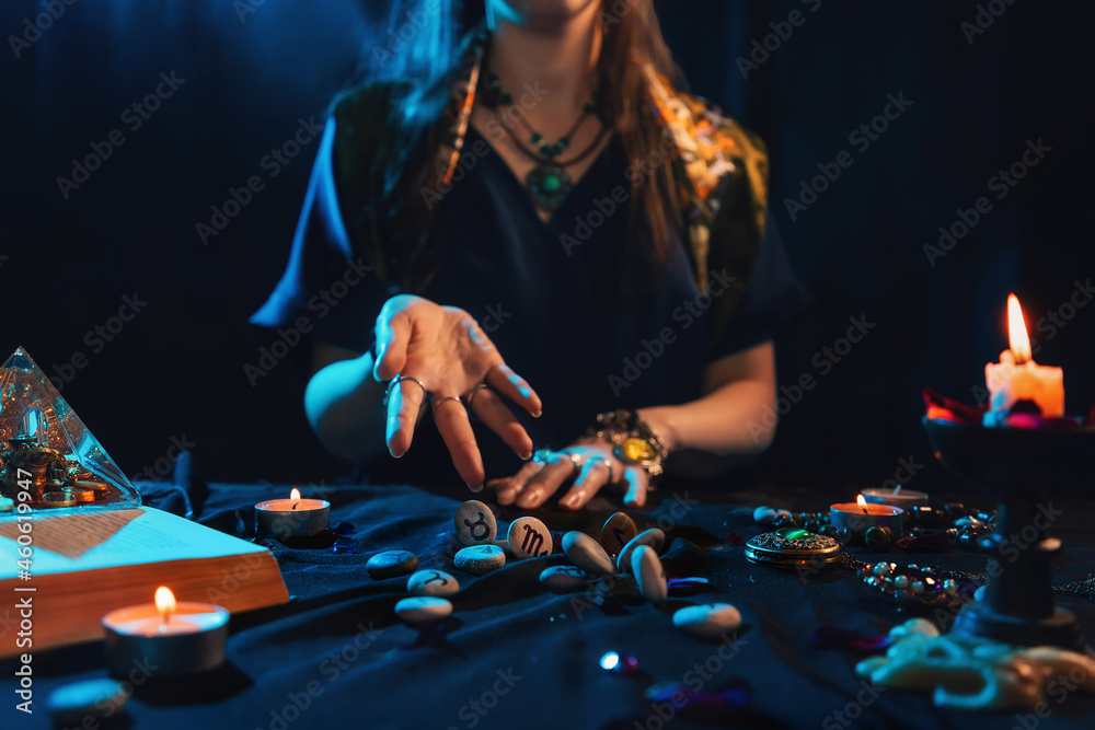 Wall mural The fortune teller throws the runestones on the table. Close-up. The concept of magic, witchcraft and divination