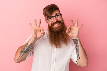 Young caucasian ginger man with long beard isolated on pink background cheerful and confident...