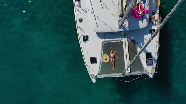 Woman in bikini tanning and relaxing on a summer catamaran sailing cruise