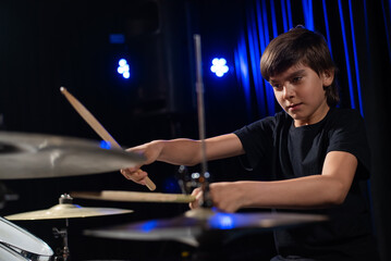 A boy plays drums in a recording studio